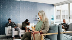 An older woman is sitting in a waiting room with other people